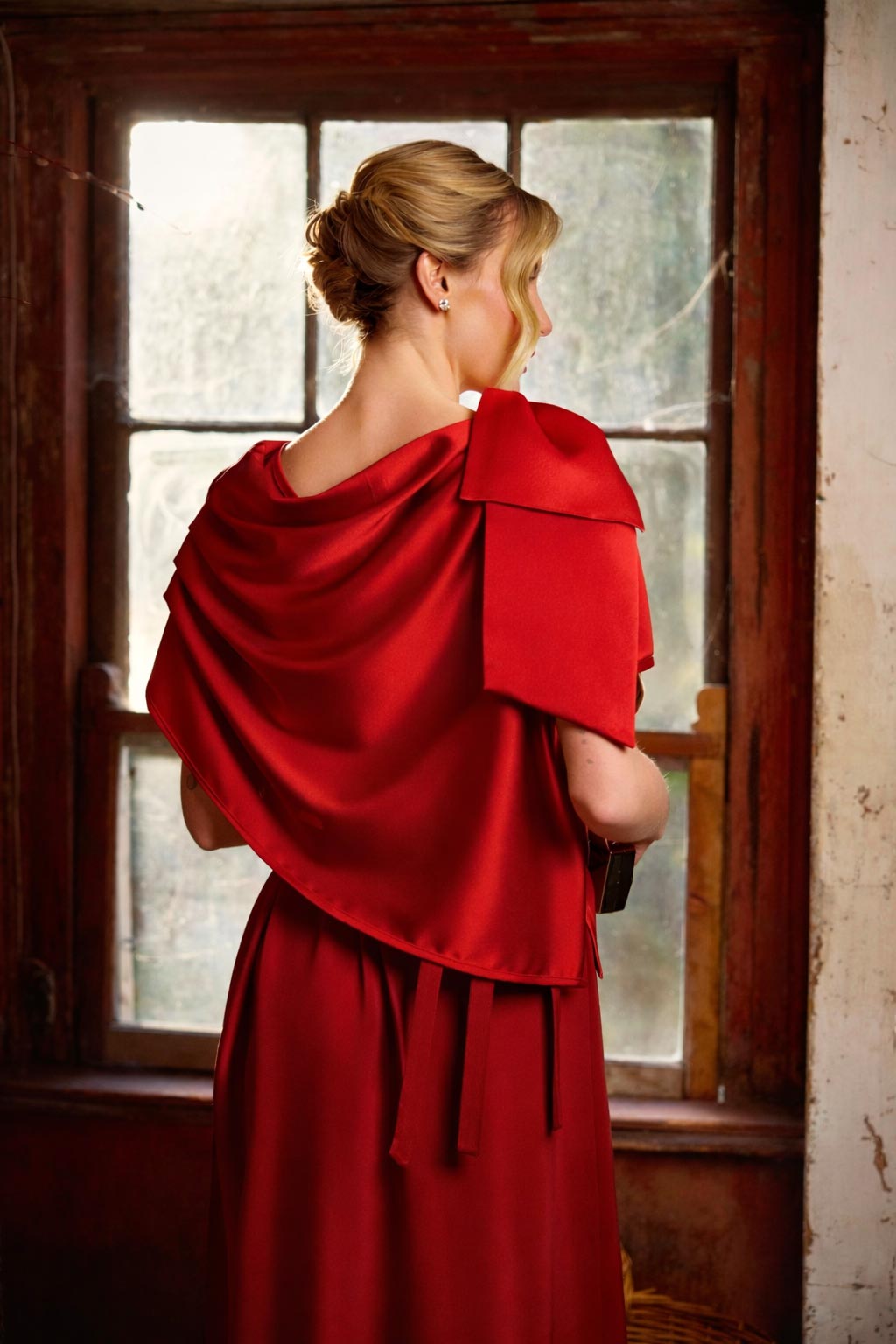Woman in a red dress standing in front of a window