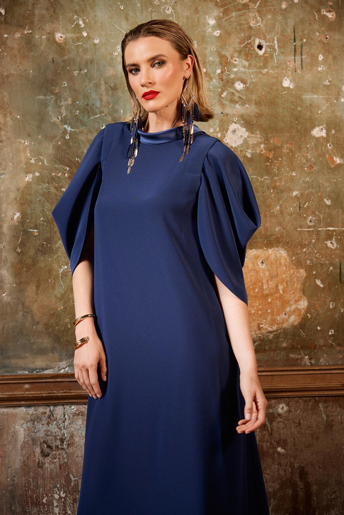Woman wearing a navy blue dress against a textured wall.