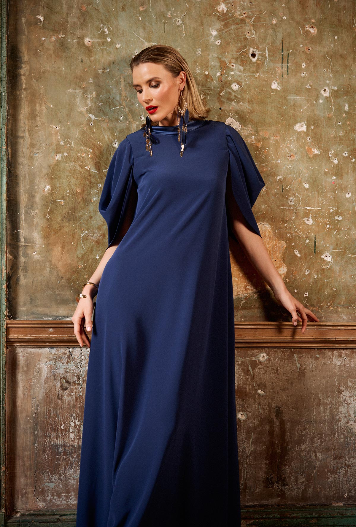 Woman wearing a navy blue dress against a textured wall.