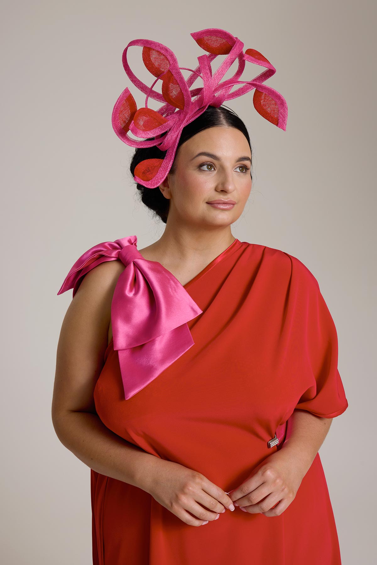 Woman in red dress and pink head piece looking away.