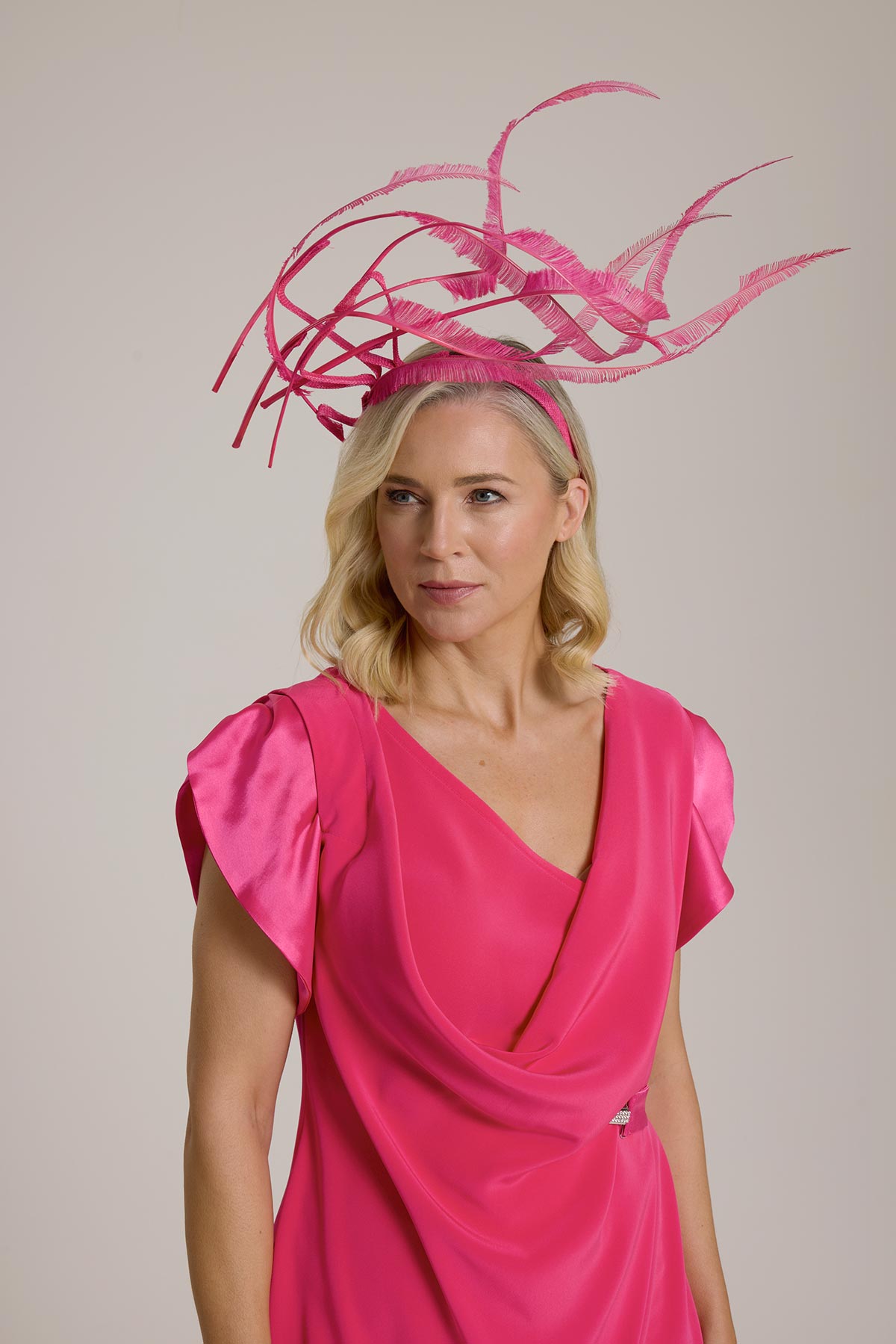 Woman wearing a vibrant pink dress and a pink feather headpiece.
