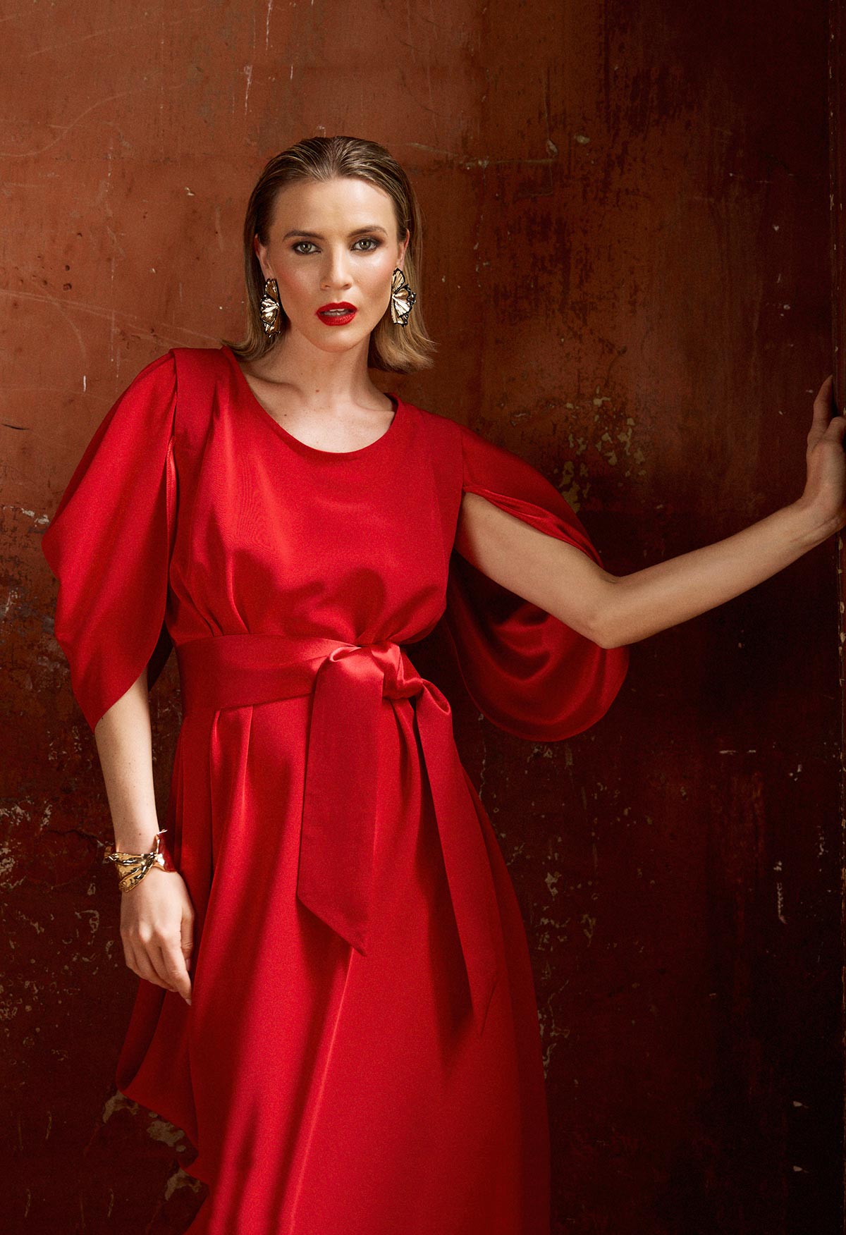 Woman wearing a red dress against a textured brown wall