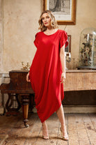 Woman in a red dress standing in an elegant room with a piano and decorative items.