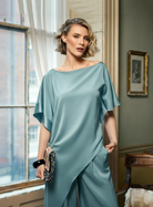 Woman wearing a duck egg dress standing in a room with a window and framed picture.