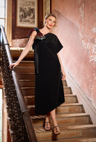 Woman in a black dress standing on a staircase with a pink wall in the background