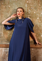 Woman wearing a blue dress against a textured wall.
