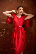 Woman wearing a red dress against a textured brown wall