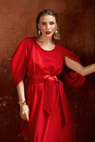 Woman wearing a red dress against a textured brown wall