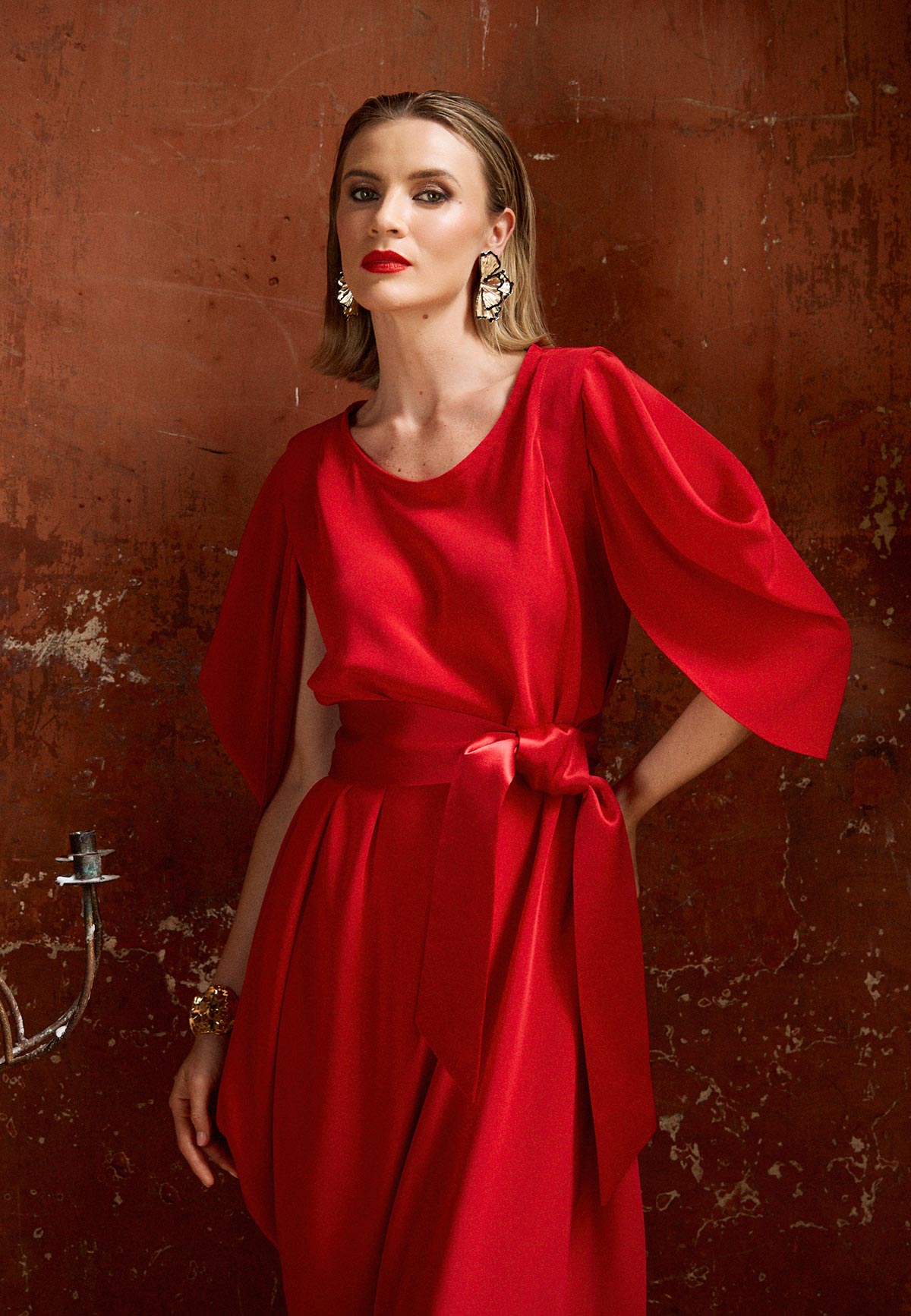 Woman wearing a red dress against a textured brown wall