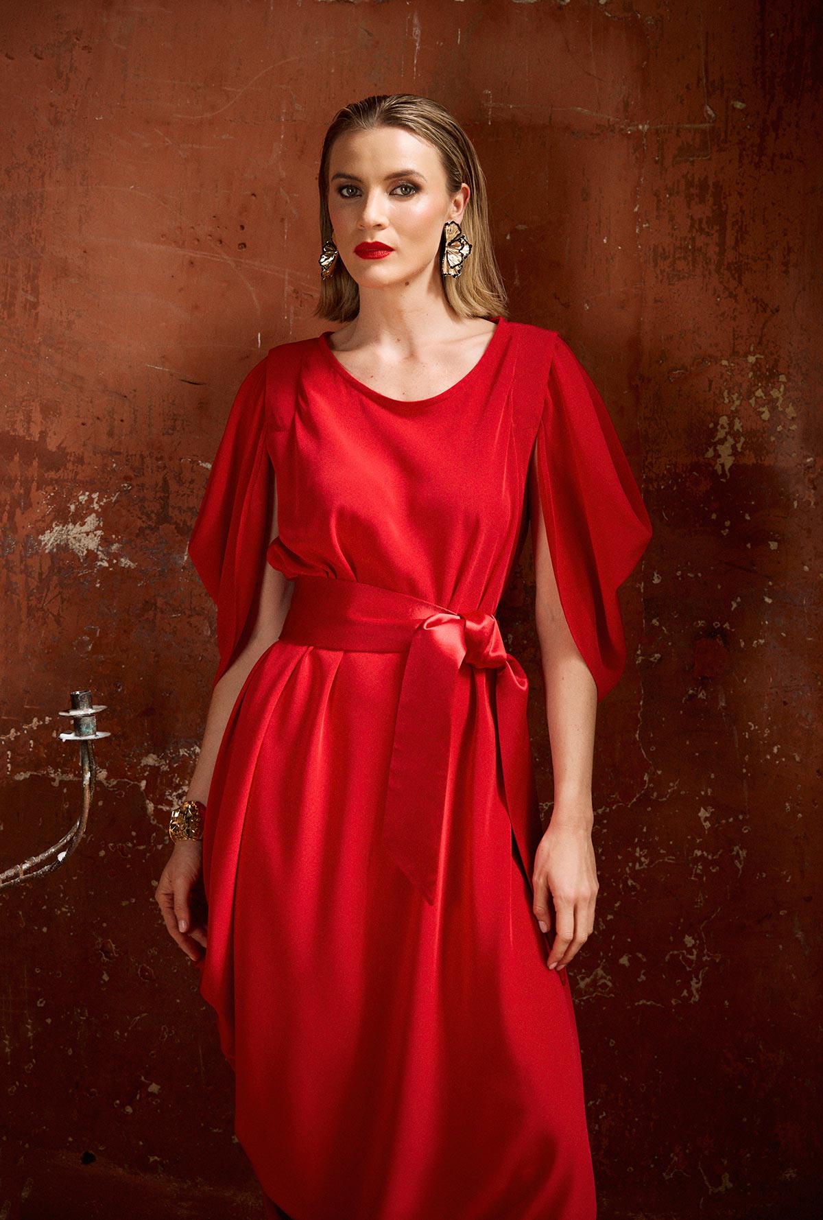 Woman wearing a red dress against a textured brown wall