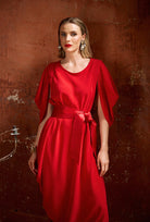 Woman wearing a red dress against a textured brown wall