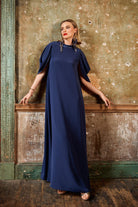 Woman wearing a navy blue dress standing against a textured wall.