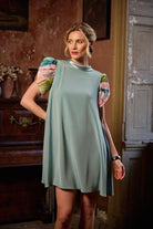 Woman wearing a light green dress with colorful sleeves in an indoor setting.