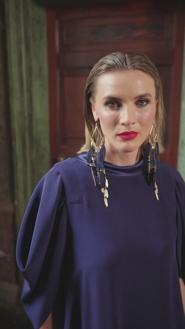video of a blonde hair woman wearing navy bue dress and large gold earings