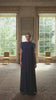 video of a woman in a long navy dress against large windows