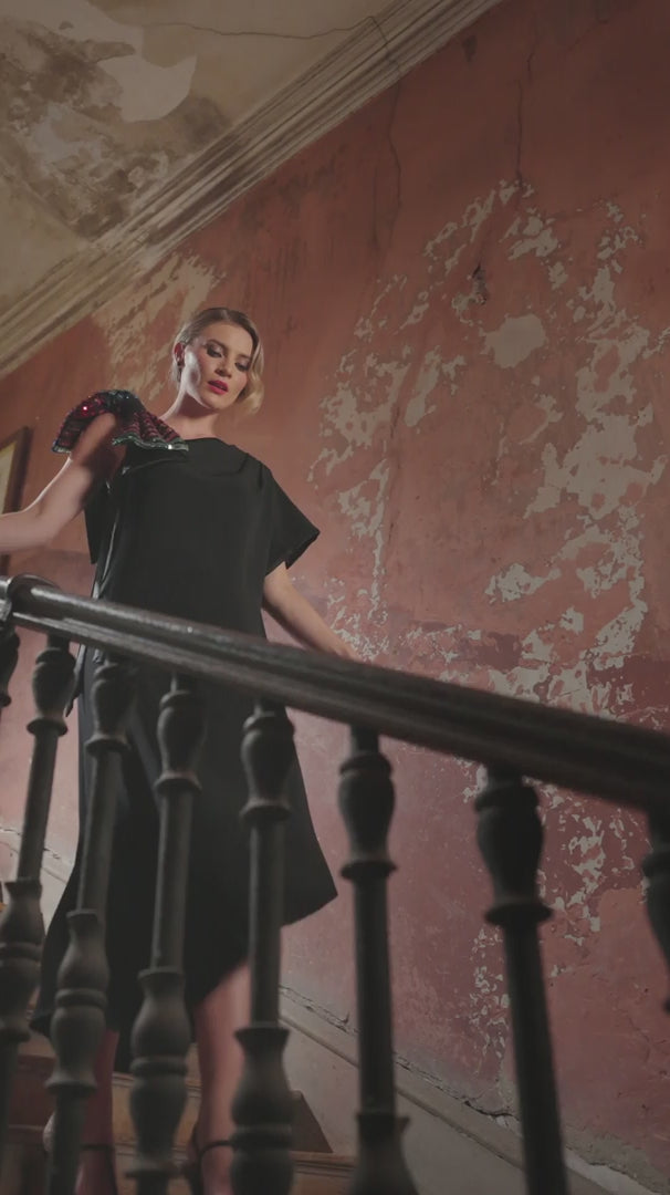 video of a woman in a black dress with sequin shoulder bow