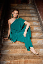 Woman in a teal top and trousers sitting on a staircase