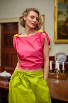 Woman wearing a pink top and lime yellow skirt in an elegant room with a painting on the wall.
