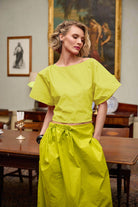 Woman wearing a bright yellow outfit in an indoor setting with furniture and artwork.