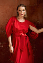 Woman wearing a red dress against a textured brown background